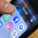 Hand holding phone with social media apps pulled up on screen